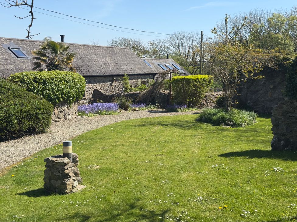 A garden with flowers and a stone wall at 8 Rogeston Cottages Haverfordwest