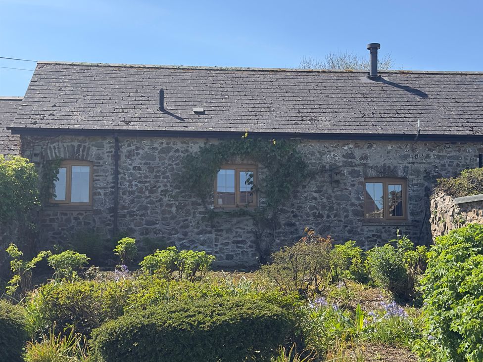 A house with stone walls and windows surrounded by a garden at 8 Rogeston Cottages in Haverfordwest