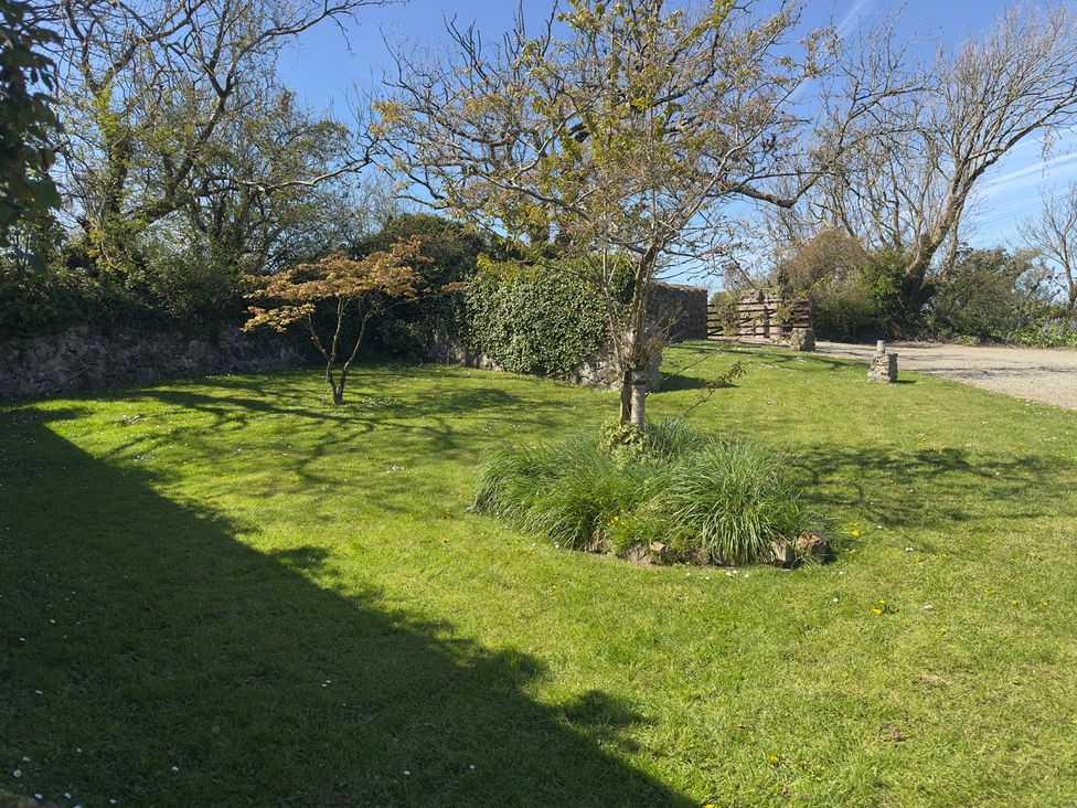 A garden with trees and a gate at 8 Rogeston Cottages Haverfordwest