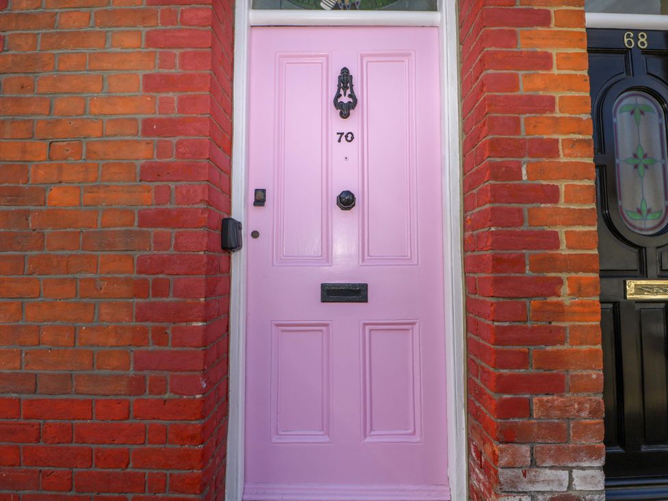 A pink door with number 70 and a black door next to it at 70 High Street in Canterbury