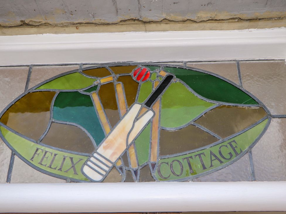 A stained glass window featuring a cricket bat and ball at Felix Cottage in Canterbury