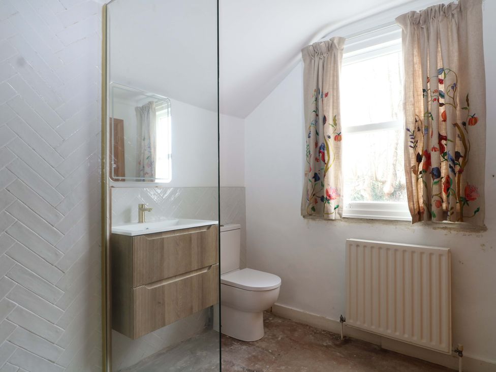A bathroom with a sink, mirror, toilet, and window at 70 High Street Canterbury
