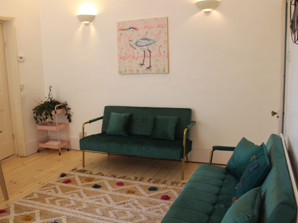 A living room with a green sofa and painting at Felix Cottage in Canterbury