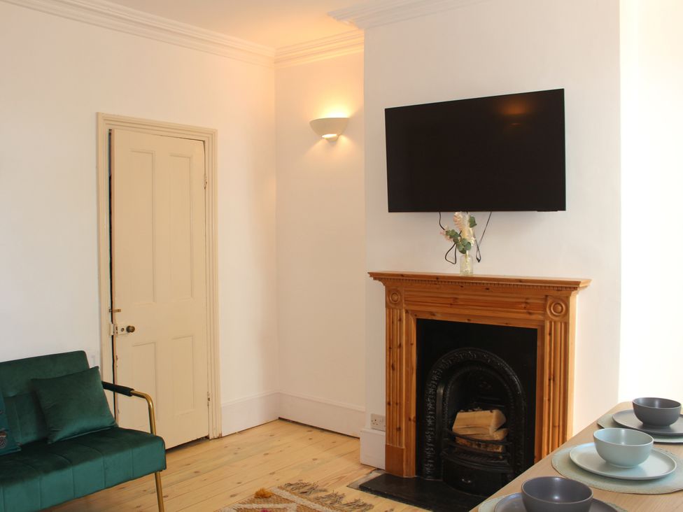 A sitting room with a fireplace and television at Felix Cottage in Canterbury