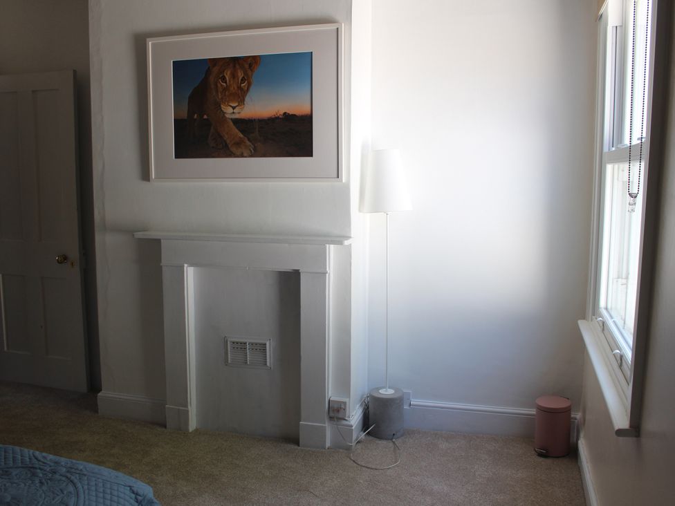 A bedroom with a fireplace and a lamp at Felix Cottage in Canterbury