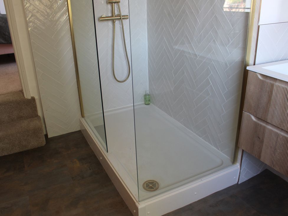 A shower with glass panel at Felix Cottage in Canterbury
