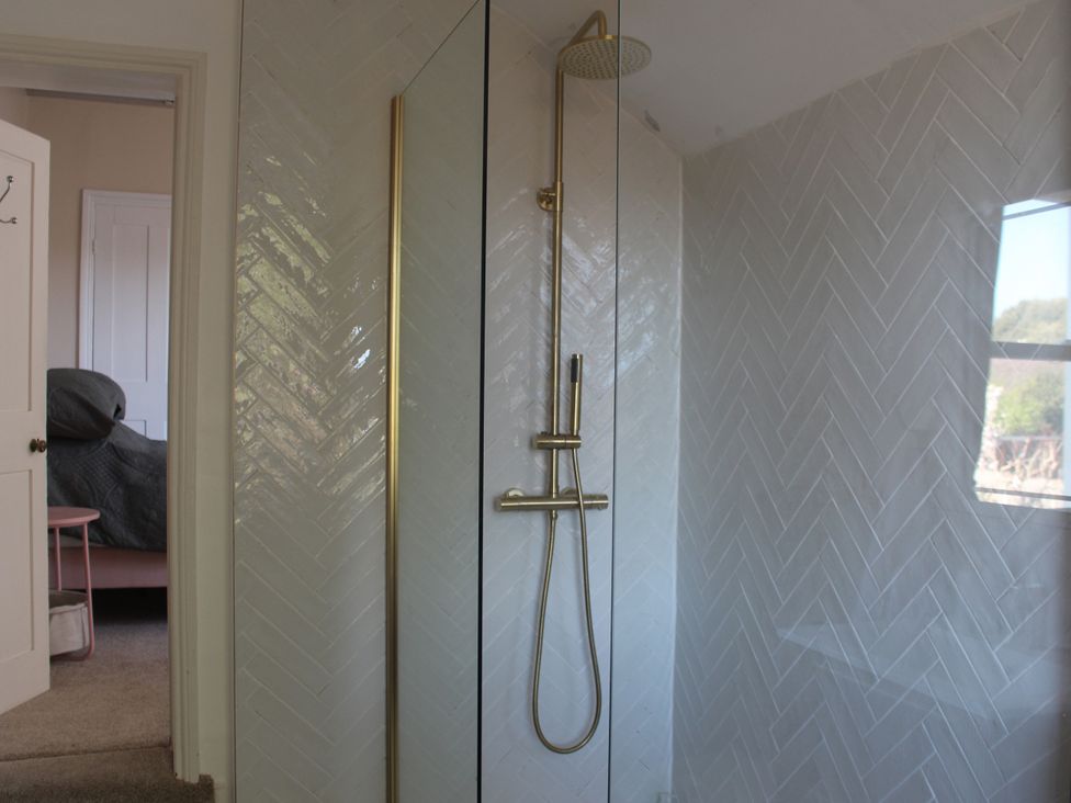 A shower with gold fixtures at Felix Cottage in Canterbury