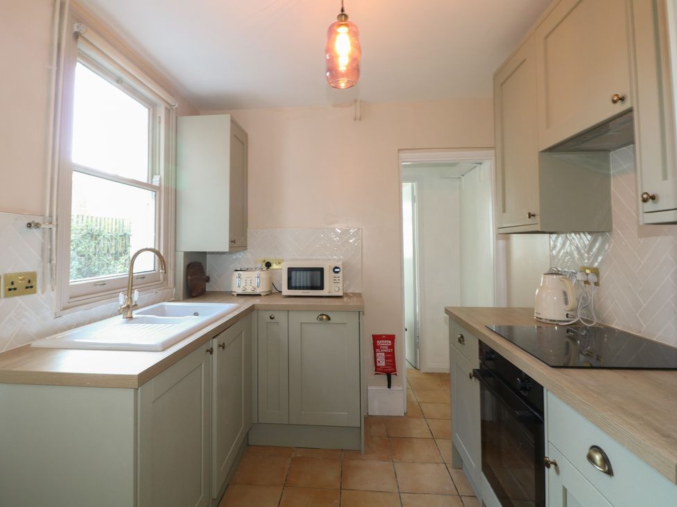 A kitchen with a sink, microwave, and cupboards at Felix Cottage in Canterbury