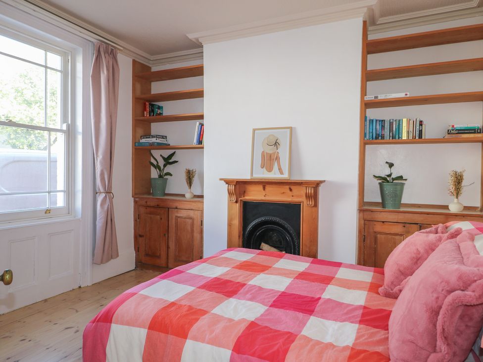 A bedroom with a bed and bookshelf at Felix Cottage in Canterbury