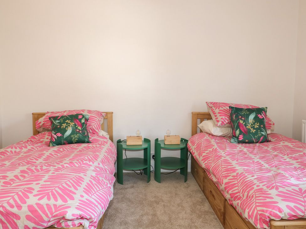 A bedroom with two beds and bedside tables at Felix Cottage in Canterbury