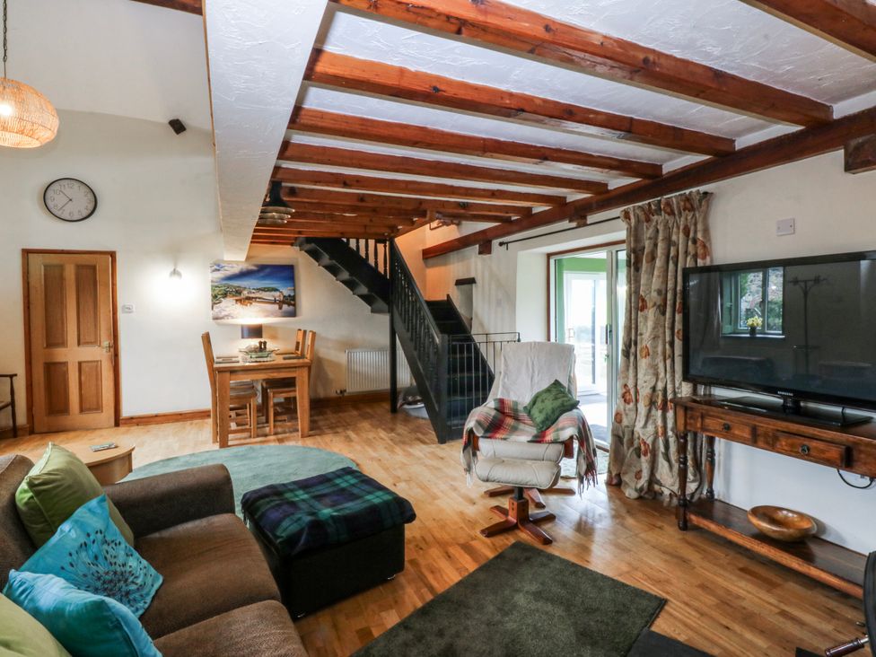 A living room with a sofa and staircase at Pen Glorian in Conwy