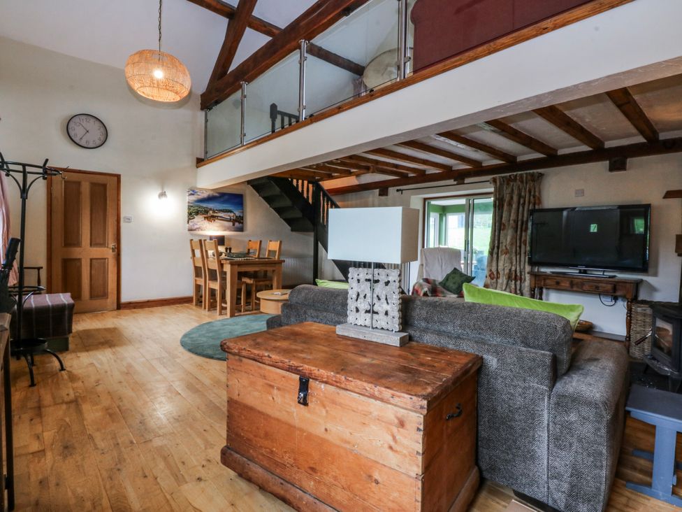 A living room with a sofa and dining area at Pen Glorian in Conwy