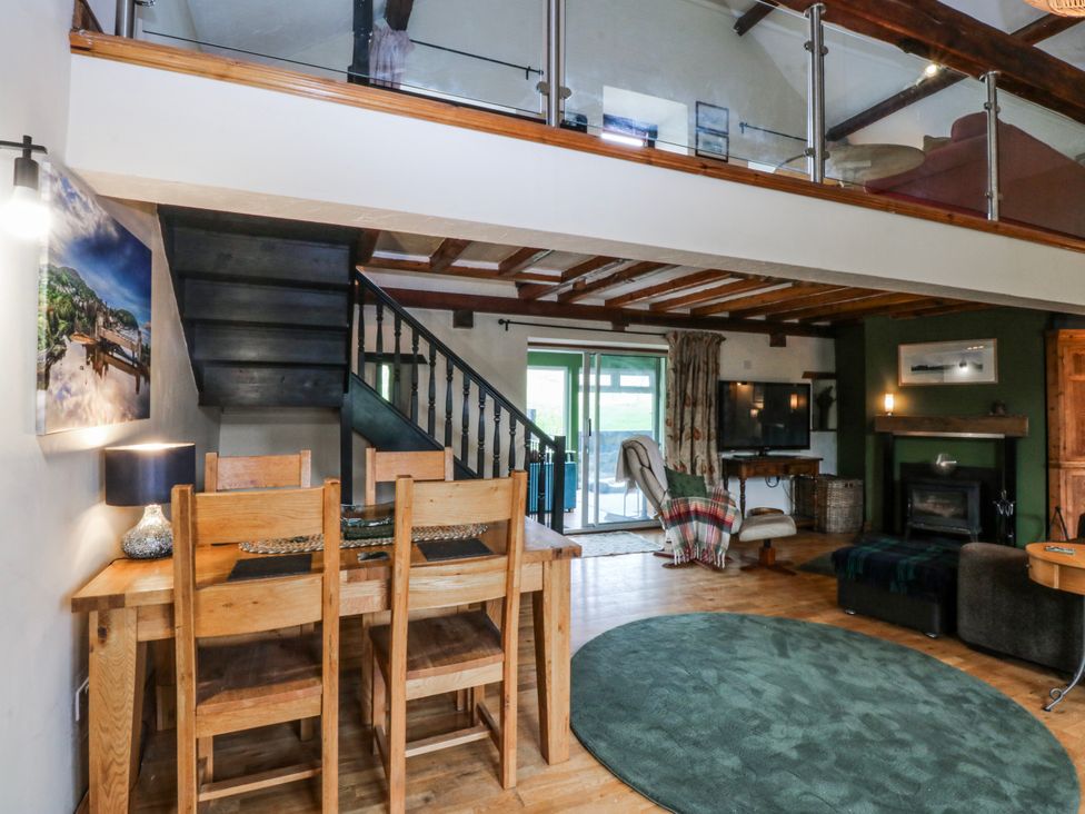 A living room with a dining area and staircase at Pen Glorian in Conwy