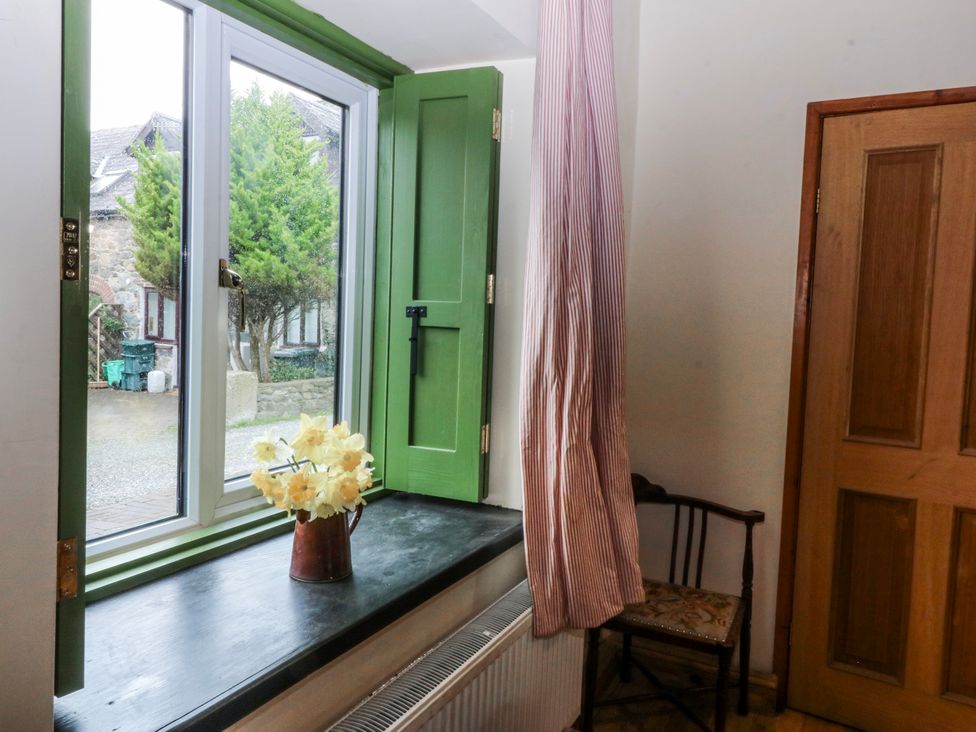 A window with flowers in a vase and a chair at Pen Glorian in Conwy