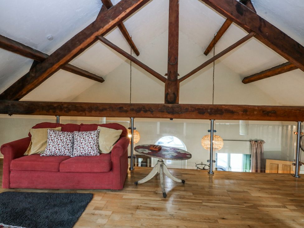 A loft area with a sofa and table at Pen Glorian in Conwy