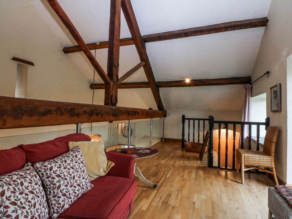 A loft with a sofa and wooden beams at Pen Glorian in Conwy