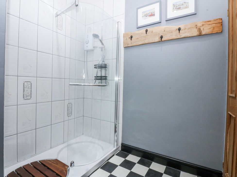 A bathroom with a shower and wooden shelf at Pen Glorian in Conwy
