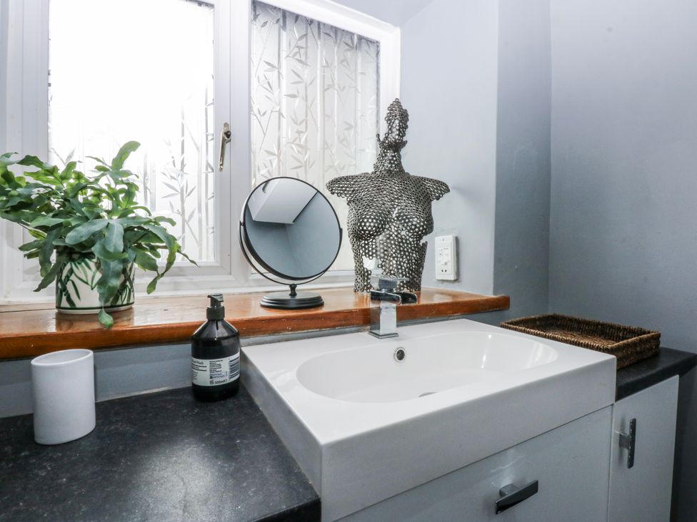 A bathroom with a sink and a mirror at Pen Glorian in Conwy