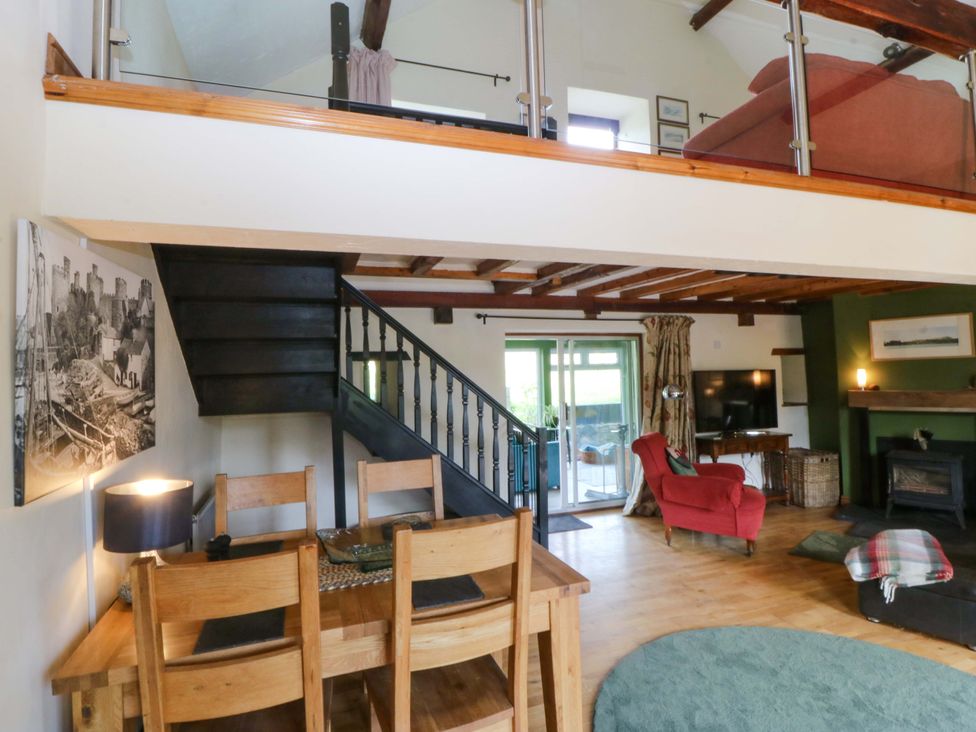 A living room with stairs and dining table at Pen Glorian in Conwy