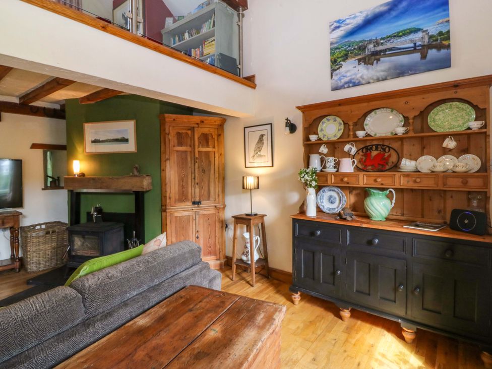 A living room with a sofa and wooden furniture at Pen Glorian in Conwy
