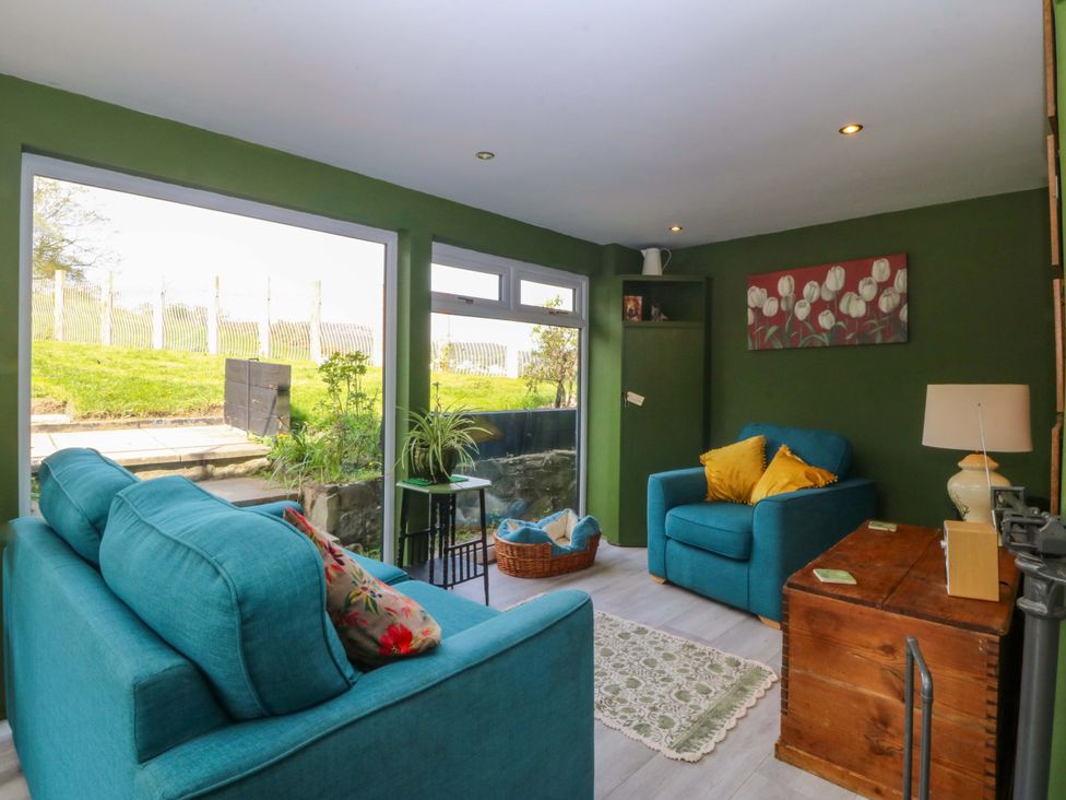 A snug with a blue couch and armchair at Pen Glorian in Conwy