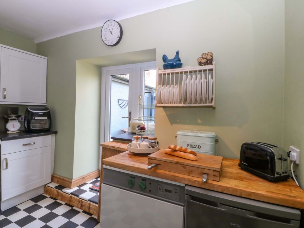 A kitchen with a clock and dish rack at Pen Glorian in Conwy