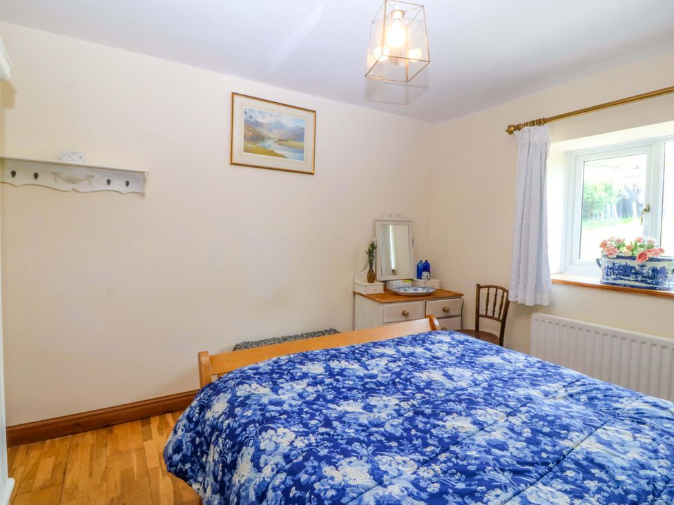 A bedroom with a bed and a mirror at Pen Glorian in Conwy