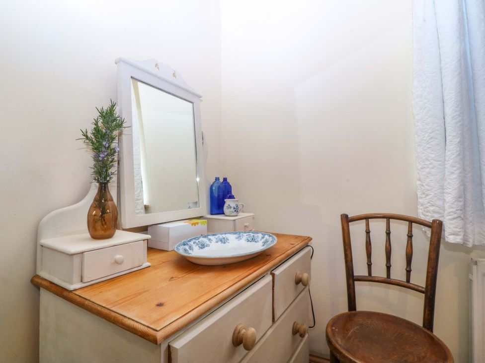 A bathroom with a vanity and mirror at Pen Glorian in Conwy