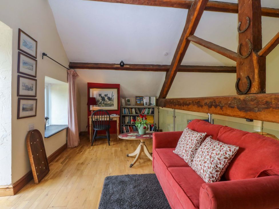 A living room with a sofa and bookshelf at Pen Glorian in Conwy