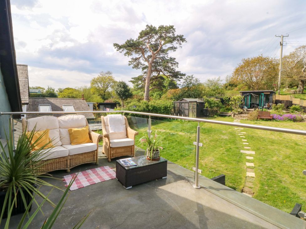 A balcony with seating and a view of a garden at Pen Glorian in Conwy