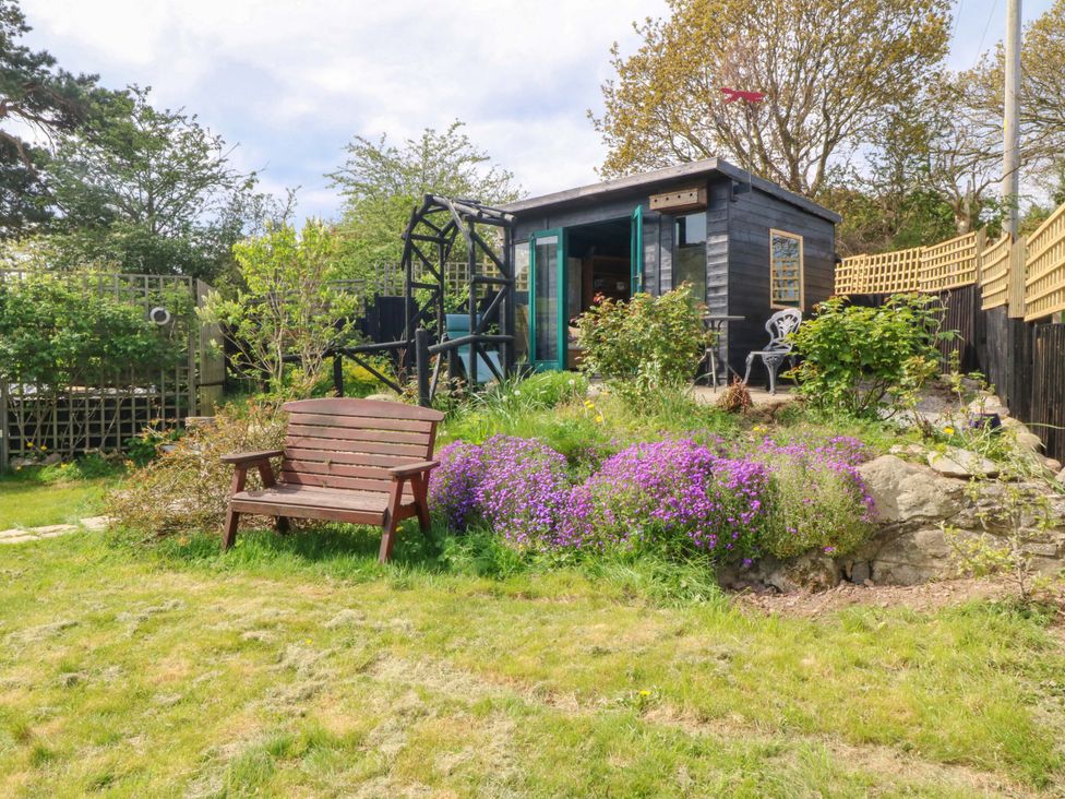 A garden with a wooden shed and bench at Pen Glorian in Conwy