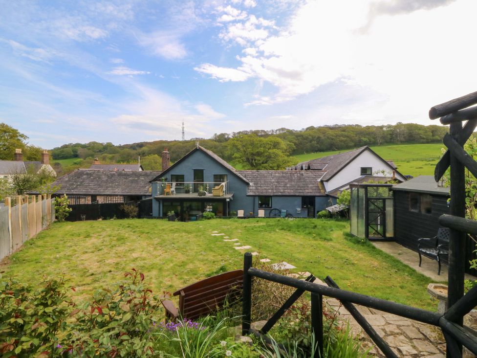 A garden view with a house and surrounding landscape at Pen Glorian in Conwy