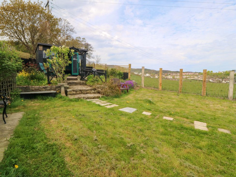 A garden with a shed, grass, steps, and a fence at Pen Glorian in Conwy