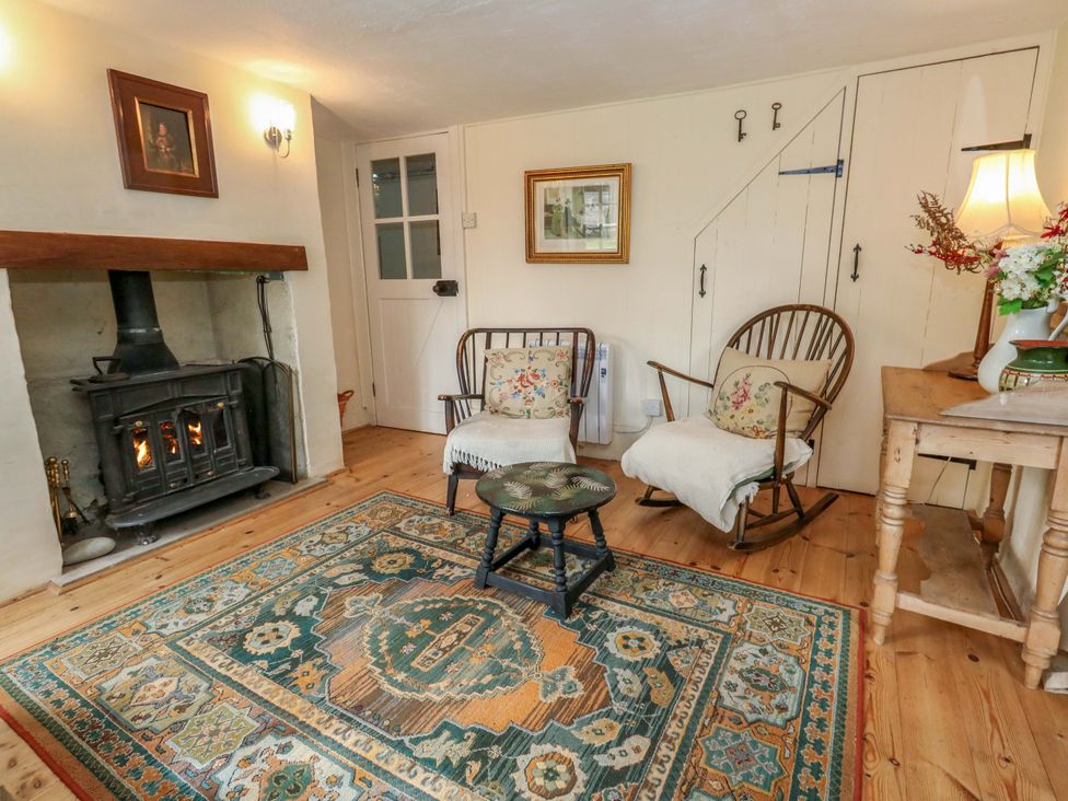 A living room with a fireplace and chairs at Little Orchard in Chard