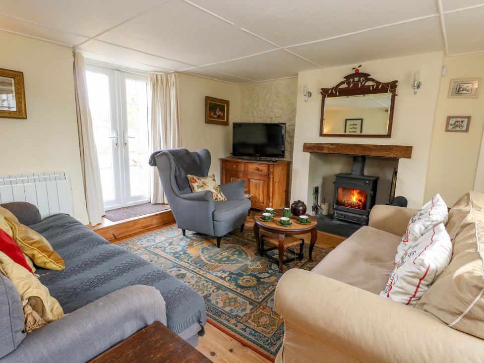 A living room with a fireplace and television at Little Orchard in Chard