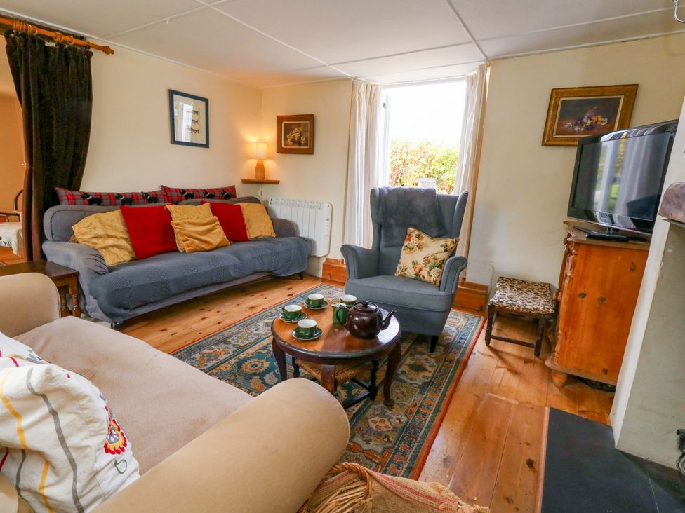 A living room with a sofa and armchair at Little Orchard in Chard