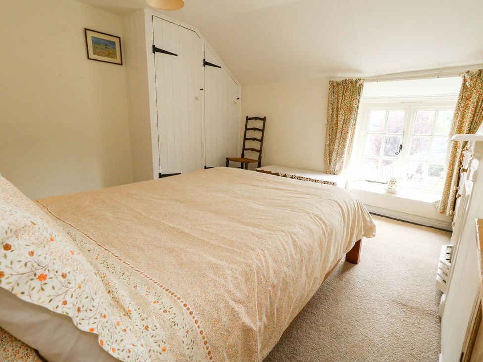 A bedroom with a bed, wardrobe, and window at Little Orchard in Chard