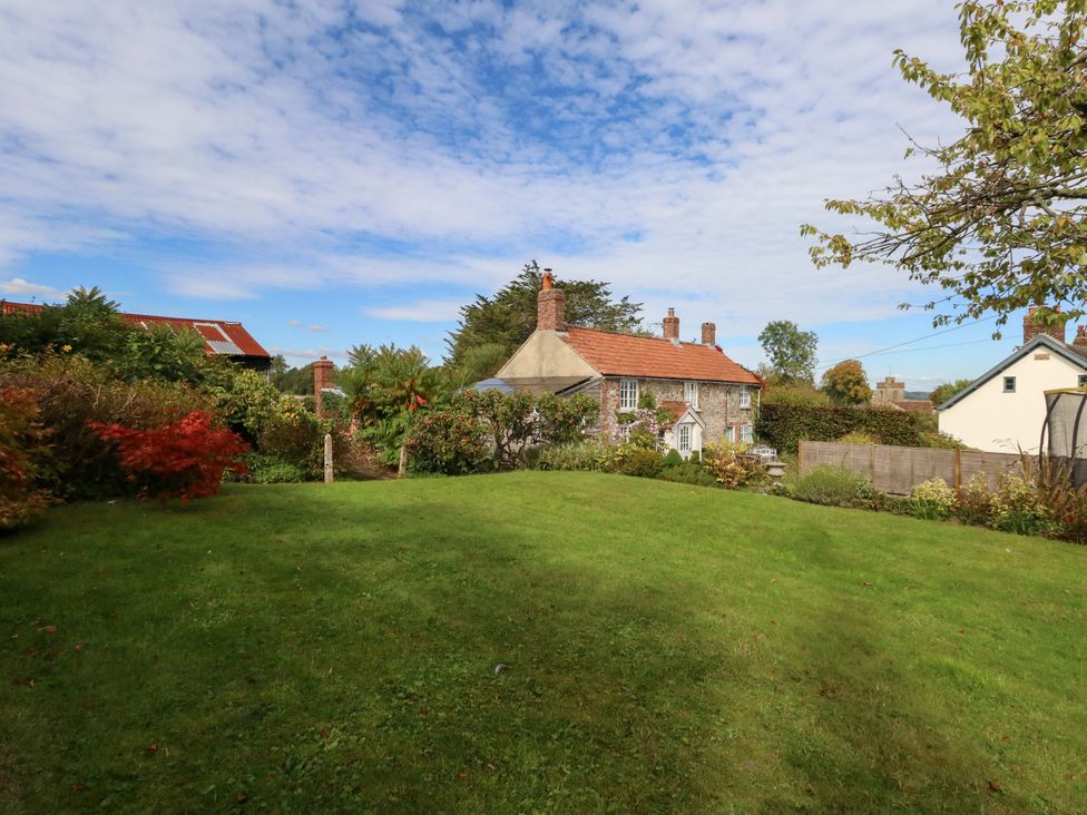 A garden with a house and trees at Little Orchard in Chard