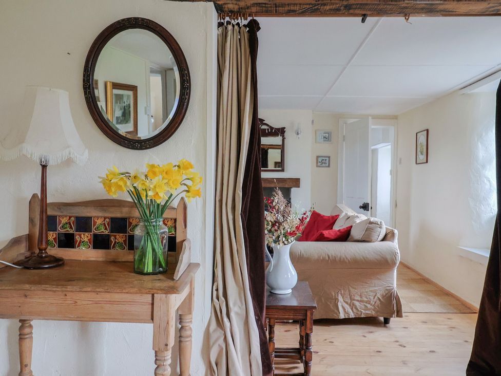 A living room with a table, lamp and flowers at Little Orchard in Thorncombe Nr. Chard
