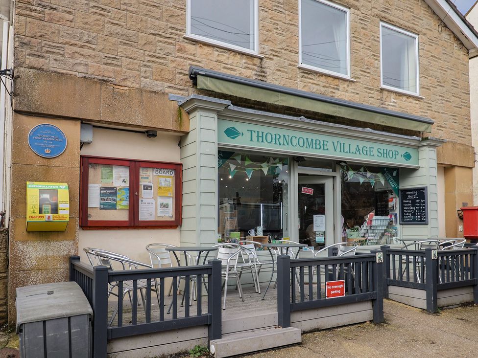 A village shop exterior with signage and chairs at Little Orchard Thorncombe Nr. Chard