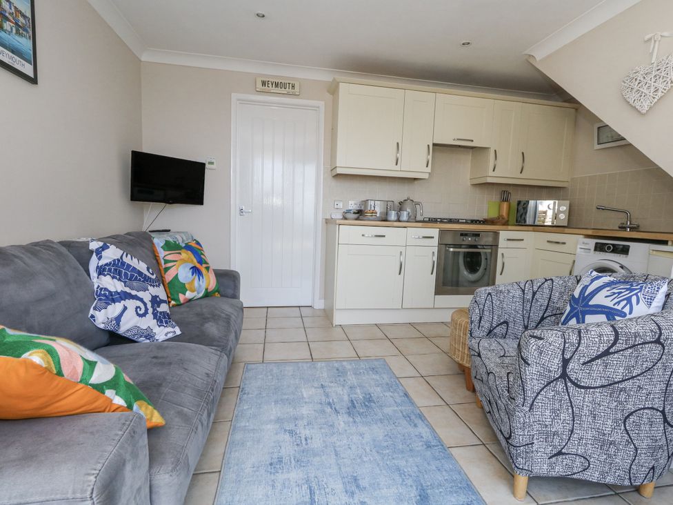 A living room with a sofa and kitchen area at Sea Spray in Bowleaze