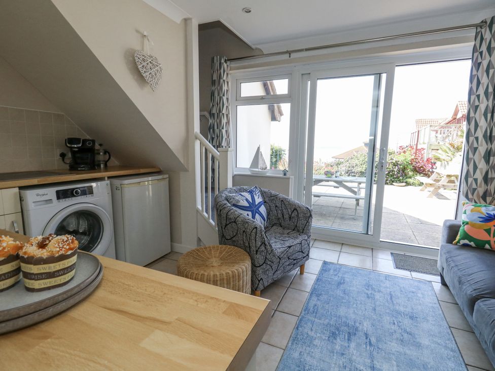 A living room with a washing machine and refrigerator at Sea Spray in Bowleaze