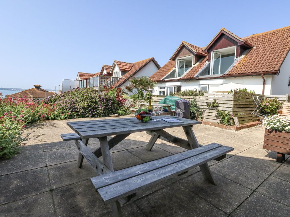 A garden with a table and benches at Sea Spray in Bowleaze