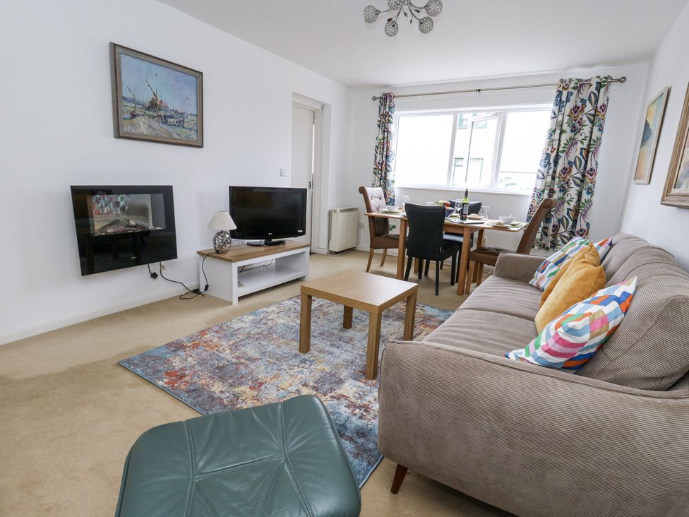 A living room with a sofa, television, and dining area at Flat 13, Chesil House, Bridport