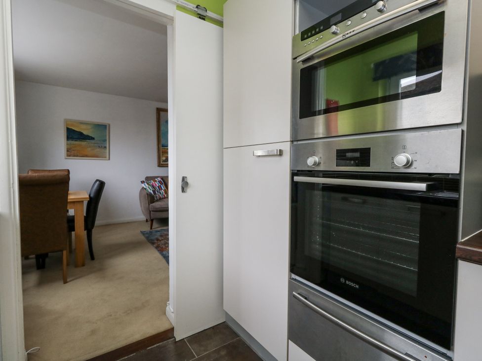 A kitchen with an oven and microwave visible from a hallway at Flat 13, Chesil House in Bridport