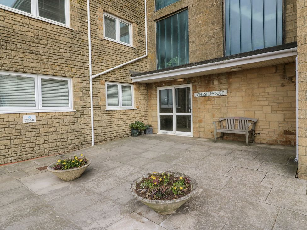 An outdoor entrance area with a bench and planters at Flat 13, Chesil House in Bridport
