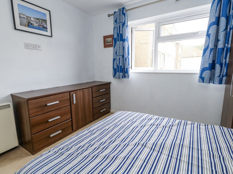 A bedroom with a bed and dresser at Beachcombers, 13 Chesil House in Bridport