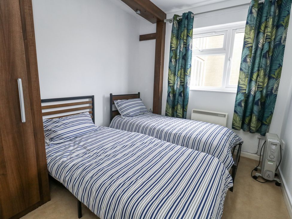 A bedroom with two single beds and a wardrobe at Beachcombers, 13 Chesil House in Bridport