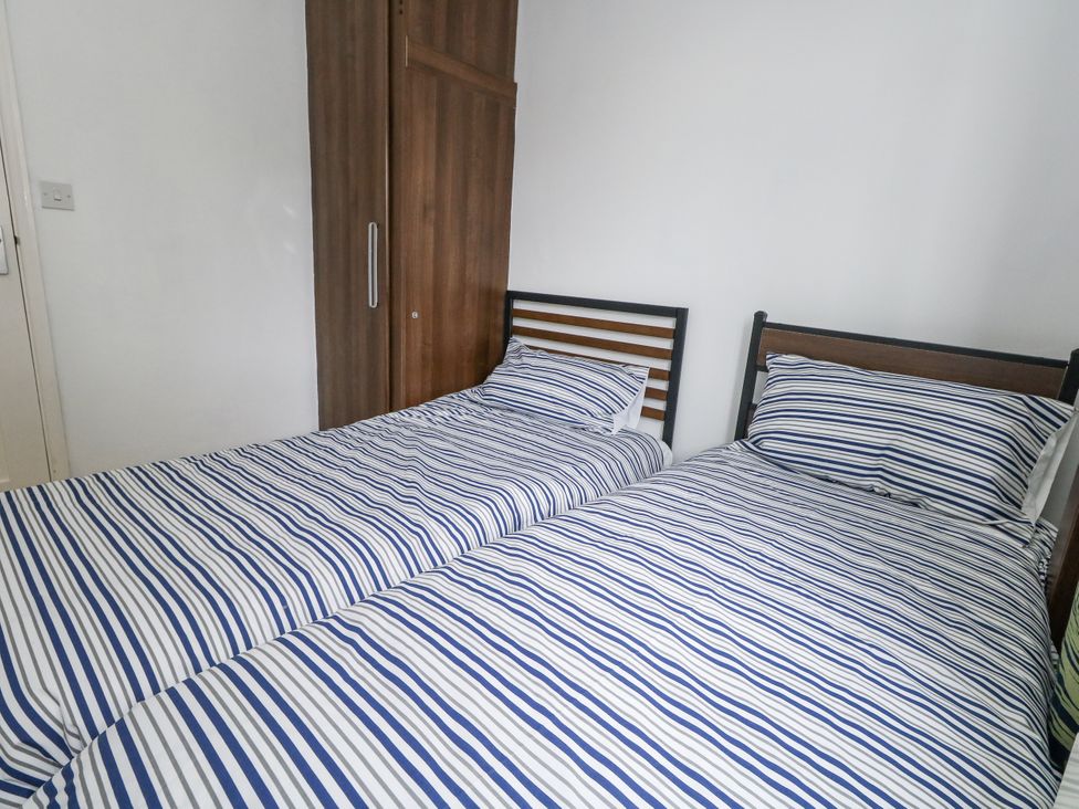 A bedroom with two beds and a wardrobe at Beachcombers, 13 Chesil House, Bridport