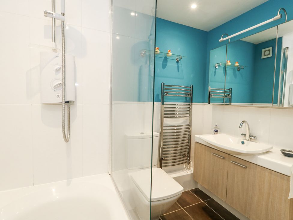A bathroom featuring a shower, bathtub, toilet, and sink at Beachcombers, 13 Chesil House in Bridport